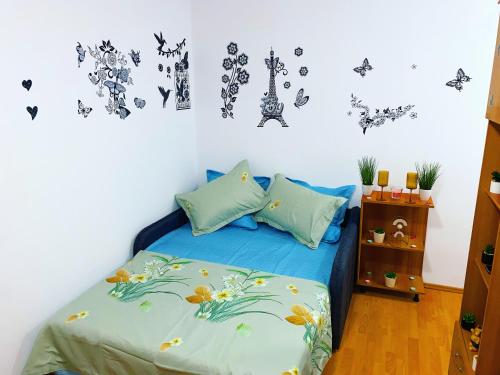 1 dormitorio con 1 cama con sábanas azules y mariposas en la pared en Casa Andu Centru, en Bucarest