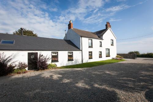 a white house with a black roof and a driveway at Manse On The Beach in Kirkistown