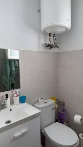 een badkamer met een toilet, een wastafel en een spiegel bij Rockside Residentes Suites La Línea N5 in La Línea de la Concepción