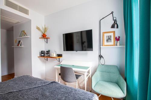 a bedroom with a desk and a chair and a tv at Hôtel Vendome Saint-Germain in Paris