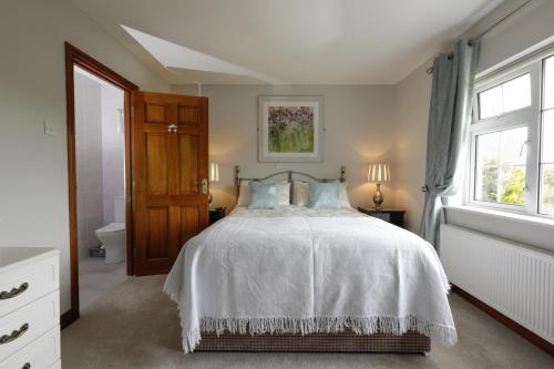a bedroom with a white bed and a window at Lurgan House in Westport