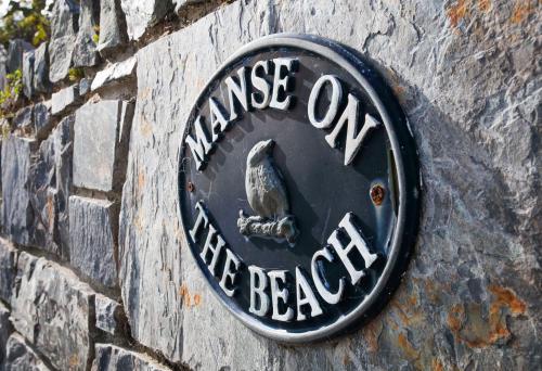 una señal en el costado de una pared de ladrillo en Manse On The Beach en Kirkistown