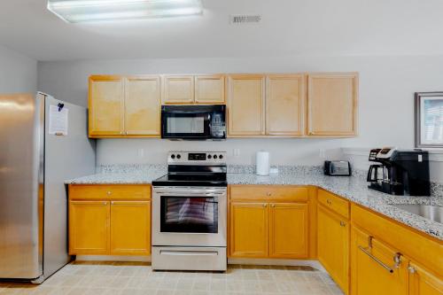 a kitchen with wooden cabinets and a stove top oven at Keys of Marsh Harbor Truman Ct in Rehoboth Beach