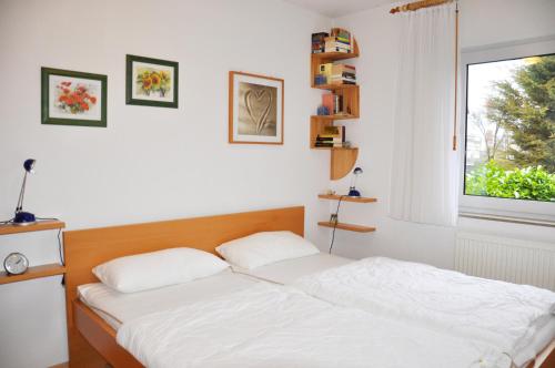 um quarto com uma cama branca e uma janela em Marienleuchte MeerLUST em Westfehmarn