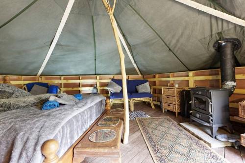 a bedroom with a tent with a bed and a stove at Hobbity Bell Hobbity log burner - Hobbity stay in Canterbury
