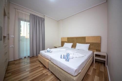 a bedroom with a large white bed with towels on it at Mamma's Apartments in Sarandë