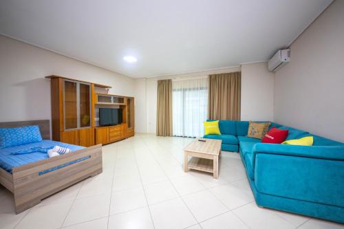 a living room with a blue couch and a tv at Mamma's Apartments in Sarandë