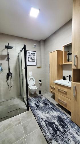 a bathroom with a shower and a toilet and a sink at Apartman Gold in Bugojno