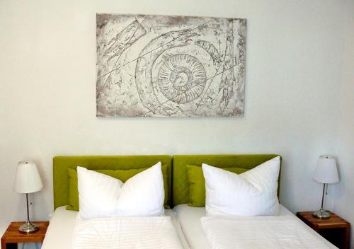 a bed with two pillows and a painting on the wall at Burghotel Lörrach in Lörrach