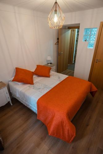 a bedroom with a bed with an orange blanket at Casa das Ruas (Xisto Sentido®) in Ameixoeira