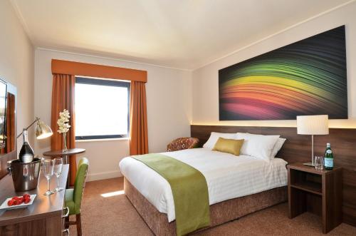 a hotel room with a bed and a colorful painting on the wall at Nox Hotel Galway in Galway