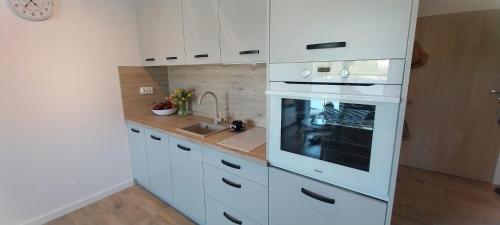a white kitchen with a stove and a sink at Apartament Garden AiR in Sztutowo