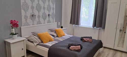 sypialnia z łóżkiem z żółtymi poduszkami i oknem w obiekcie Pompár Belvárosi Apartman w Segedynie
