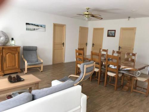 salon z kanapą, stołem i krzesłami w obiekcie Villa dans la pinède, au calme à proximité du lac et des plages, jusqu'à 7 personnes w mieście Biscarrosse