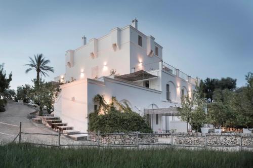 un grande edificio bianco con una recinzione di fronte di Masseria Alchimia a Fasano