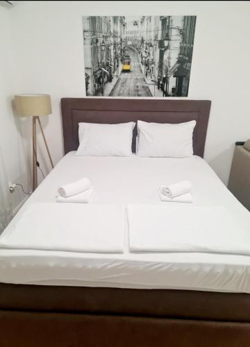 a bed with white sheets and a black and white picture on the wall at Becici Studio Apartment in Budva