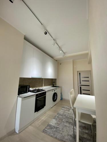 a kitchen with white cabinets and a table with chairs at A cosy apartment in Osh