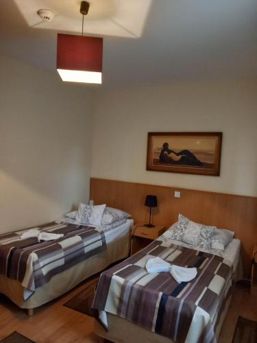 a room with two beds and a painting on the wall at Kata Panzió in Oroszlány