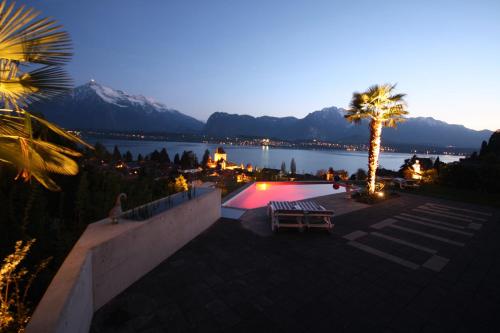 a swimming pool with a palm tree and a mountain at Otium-Oberhofen in Oberhofen am Thunersee