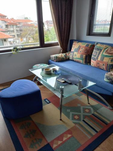uma sala de estar com um sofá azul e uma mesa de vidro em Guest house Veneta em Sozopol