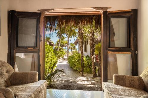 an open door to a patio with palm trees outside at Playa Esperanza Tulum in Tulum