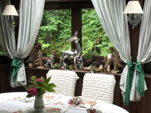 a table with two white chairs in front of a window at Penthouse-Suite Mountain View mit Waldhütte/Sauna/Netflix in Nachdemsee
