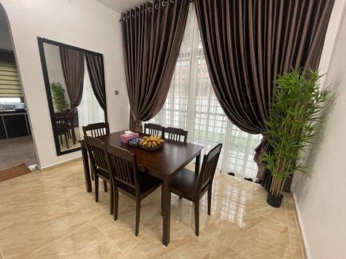 a dining room with a table and chairs and curtains at Villa President Homestay -4 bedroom Aircond WIFI Vacations Home in Kampung Kerangi