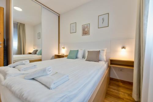 un grande letto bianco in una stanza con specchio di Appartement Vila Luxury and Spa a Zlatibor