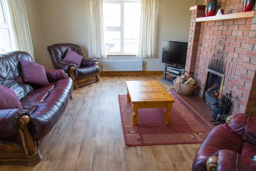a living room with leather furniture and a fireplace at Doherty's Country Accommodation in Ballyliffin