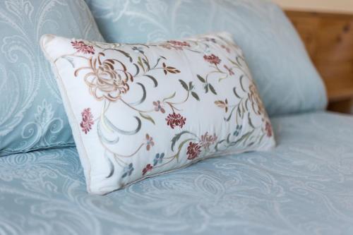 Una almohada blanca con flores rojas en un sofá azul en Doherty's Country Accommodation en Ballyliffin
