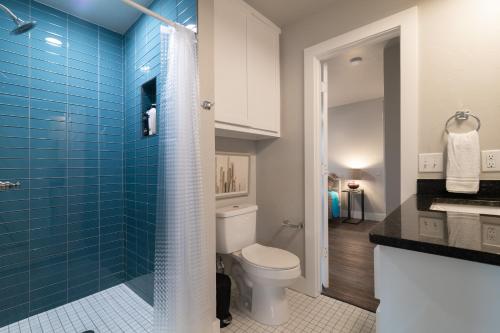 a bathroom with a toilet and a shower with blue tiles at Plaza Pad II-Near Plaza District in Oklahoma City