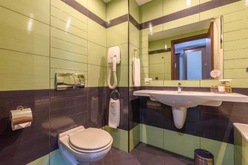 a bathroom with a sink and a toilet and a mirror at Lion Sunny Beach Hotel in Sunny Beach