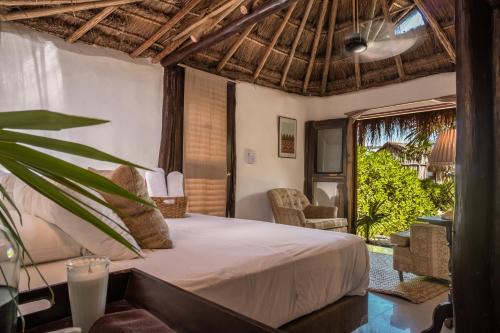 a bedroom with a bed and a large window at Playa Esperanza Tulum in Tulum