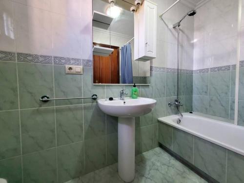een badkamer met een wastafel, een spiegel en een bad bij Magnifico apartamento en O Grove in O Grove
