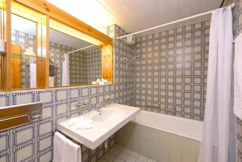 uma casa de banho com um lavatório, uma banheira e um espelho. em Apartment Schweizerhof 242 Lenzerheide em Lenzerheide