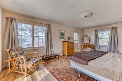 a bedroom with a bed and a chair and windows at Seaside Governor's House Vacation Rental in Seaside