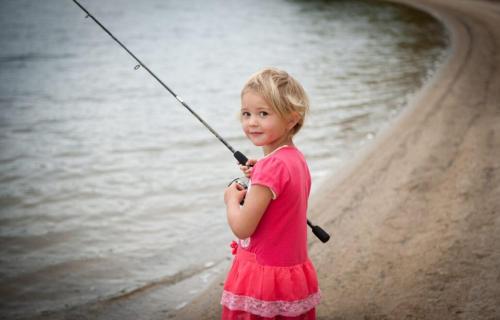 a little girl in a pink dress holding a fishing pole at Apartmány u Dlouhána in Kadaň