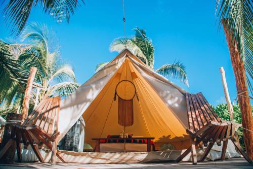 a large yellow tent with two chairs and palm trees at GlampIKAL formerly Casa Nawal in Tulum