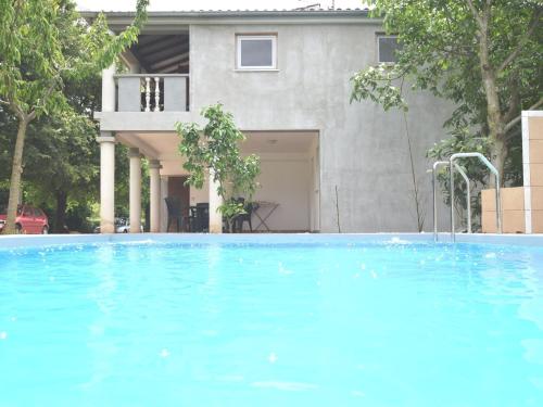 a large blue swimming pool in front of a house at Apartment in holiday home with private pool garden with grill airco and wifi in Banjole