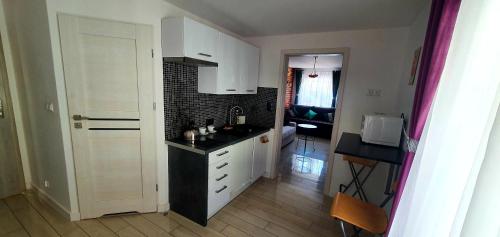 uma cozinha com armários brancos e um balcão preto em Apartamenty Orchidea Łeba em Łeba