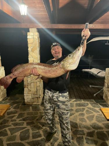 a man holding up a fish with a knife at Apartmány u Dlouhána in Kadaň