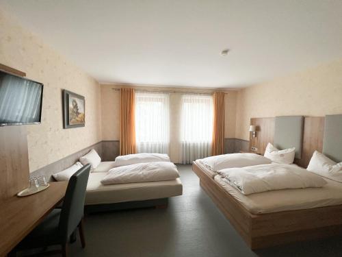 a hotel room with two beds and a desk at Hotel Garni Illertal in Altenstadt