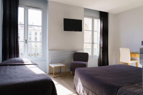 a bedroom with two beds and a chair and a tv at Hotel du Théatre in Lyon