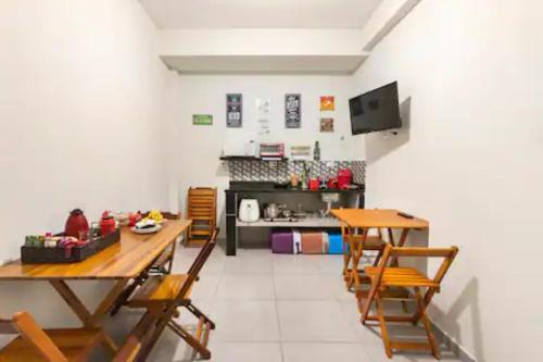 プライア・グランデにあるPousada Casa da Fernanda, Suíte Moonのテーブルと椅子2脚、キッチンが備わる客室です。