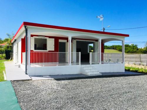 un petit bâtiment rouge et blanc avec un toit rouge dans l'établissement Maison de 2 chambres avec piscine partagee jardin clos et wifi a Le Moule a 3 km de la plage, à Le Moule