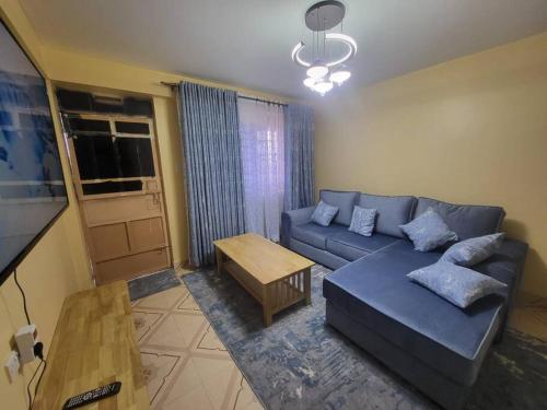 a living room with a blue couch and a table at Blue House 2 Bedroom House. in Naivasha
