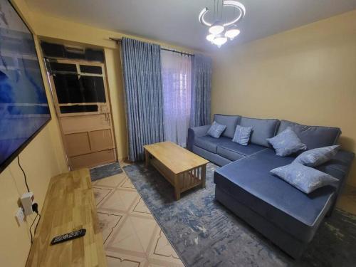 a living room with a blue couch and a table at Blue House 2 Bedroom House. in Naivasha