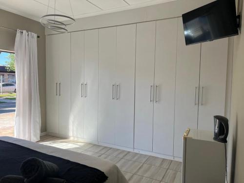 a bedroom with white cabinets and a flat screen tv at Carstens Garden Cottages in Kimberley