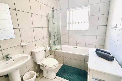 a white bathroom with a toilet and a sink at Stylish Hartenbos Apartment in Mossel Bay