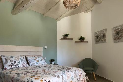 a bedroom with a bed and a green chair at Domus Deiana Case Vacanza in San Giovanni Suèrgiu